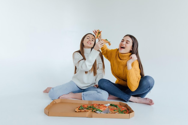 Dos amigas comiendo pizza.