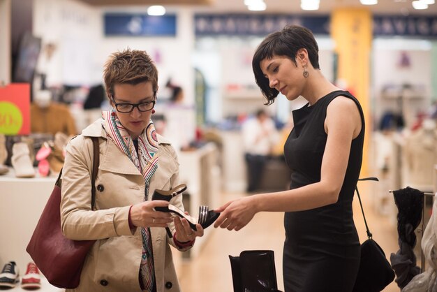 Dos amigas en compras a pie de centro comercial con bolsas y elegir