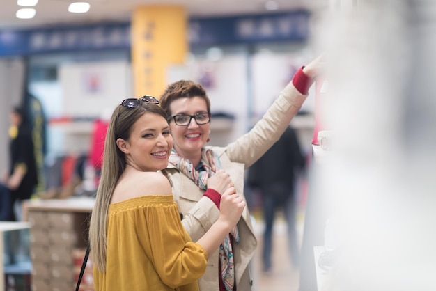 Dos amigas en compras a pie de centro comercial con bolsas y elegir