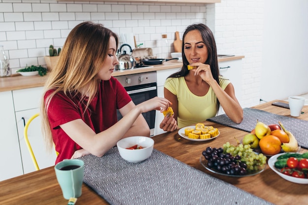 Dos amigas desayunando en la mesa de la cocina