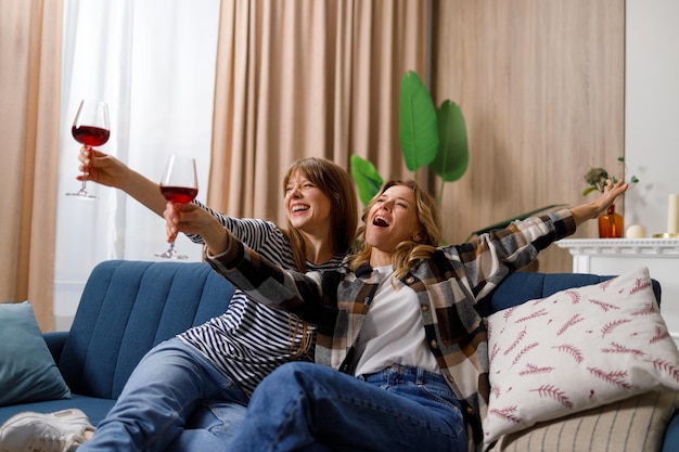 Dos amigas de diferentes edades se divierten bebiendo vino durante la fiesta en casa