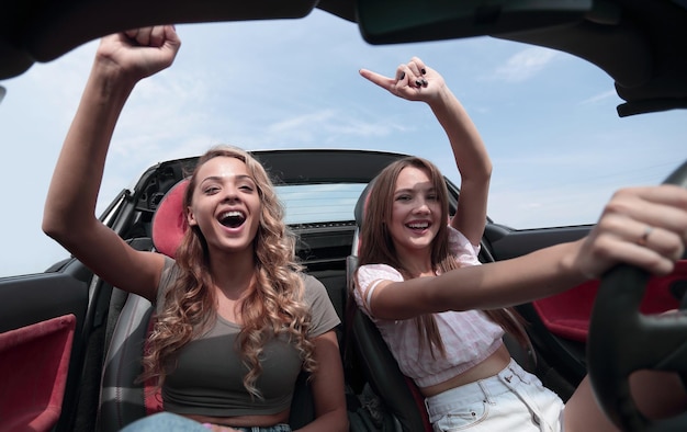 Foto dos amigas disfrutando de un viaje en el cochela libertad de la carretera abierta