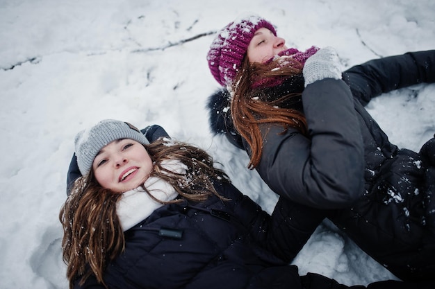 Dos amigas divertidas divirtiéndose en el día nevado de invierno cerca de árboles cubiertos de nieve