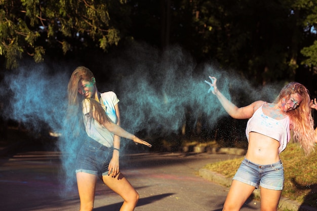 Dos amigas divertidas rubia divirtiéndose con la explosión de polvo Holi