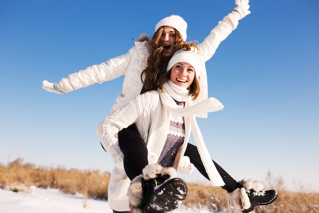 Dos amigas se divierten y disfrutan de la nieve fresca en el hermoso día de invierno