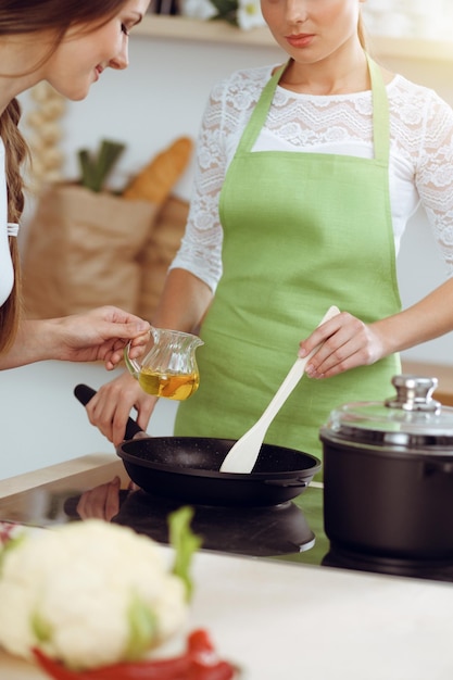 Dos amigas eligen la receta y los ingredientes para una deliciosa comida en la cocina soleada Concepto vegetariano