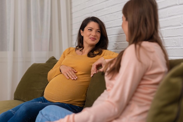 Dos amigas embarazadas hablando en interiores. Comparten consejos de embarazo y bebé