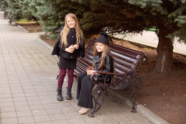 dos amigas están sentadas en un banco del parque con cacao en las manos, charlando dulcemente