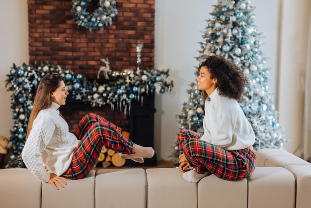 Dos amigas estudiantes sentadas en el sofá en casa