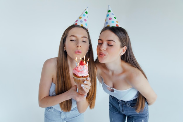 Dos amigas europeas ropa sombreros de cumpleaños posando. Concepto de estilo de vida de las personas.