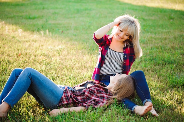 Dos amigas felices jugando y divirtiéndose en la hierba verde