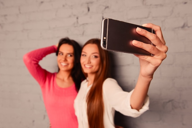 Dos amigas hacen fotos selfie en un teléfono móvil