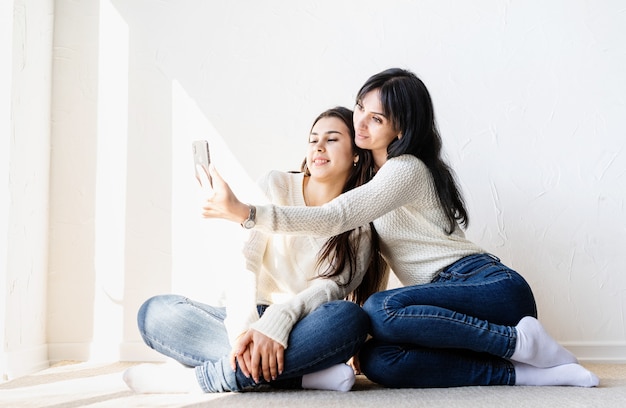 Dos amigas hermosas tomando selfie en teléfono móvil haciendo muecas