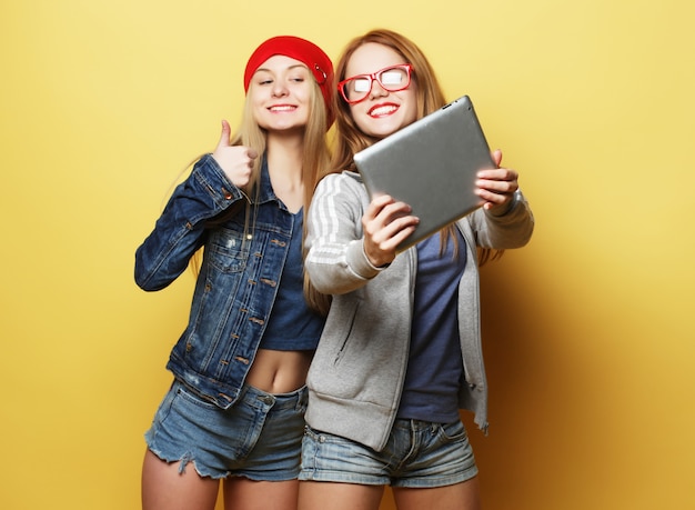 Dos amigas hipster tomando selfie con tableta digital