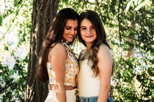 Dos amigas jóvenes en el bosque con árboles en el fondo