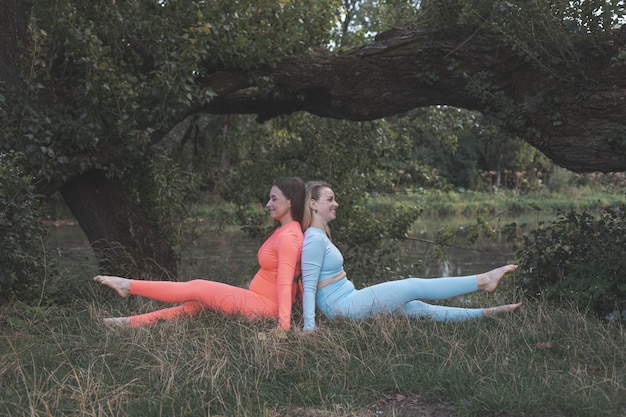 Dos amigas jóvenes felices practican yoga al aire libre
