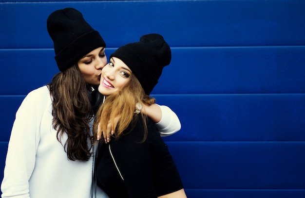 Dos amigas jóvenes hipster divirtiéndose juntos. Al aire libre, estilo de vida.