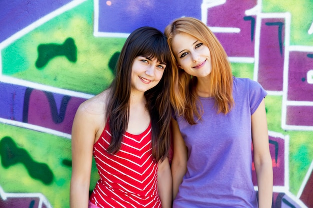 Foto dos amigas junto a la pared de graffiti.