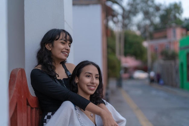 Dos amigas latinas abrazadas en la calle al atardecer