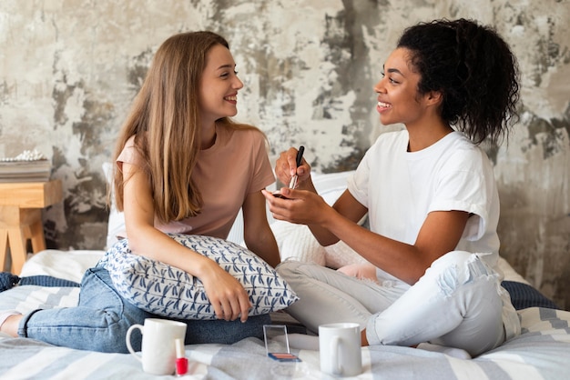 Dos amigas con maquillaje en casa en la cama