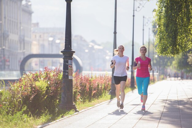 dos amigas de mediana edad trotando tienen entrenamiento matutino con el amanecer en el fondo