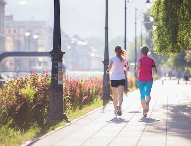 dos amigas de mediana edad trotando tienen entrenamiento matutino con el amanecer en el fondo