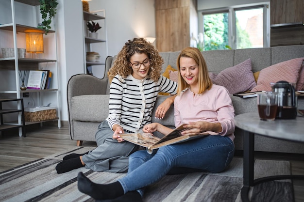 Dos amigas mirando un viejo álbum de fotos en casa