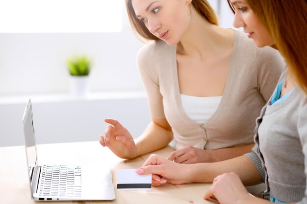 Dos amigas o hermanas hablando conversando en la mesa con una laptop mirándose