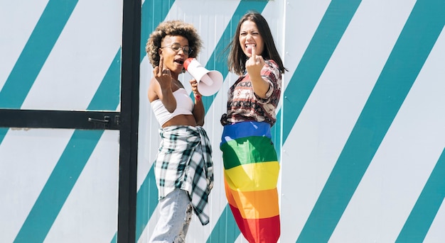 Dos amigas pasando el rato en la ciudad ondeando LGBT con bandera de orgullo