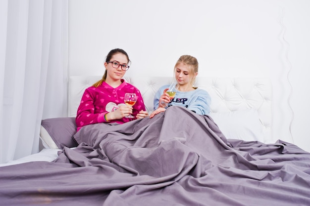 Dos amigas en pijama divirtiéndose en la cama en la habitación