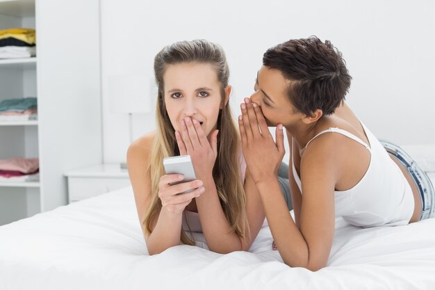 Dos amigas relajadas chismeando en la cama