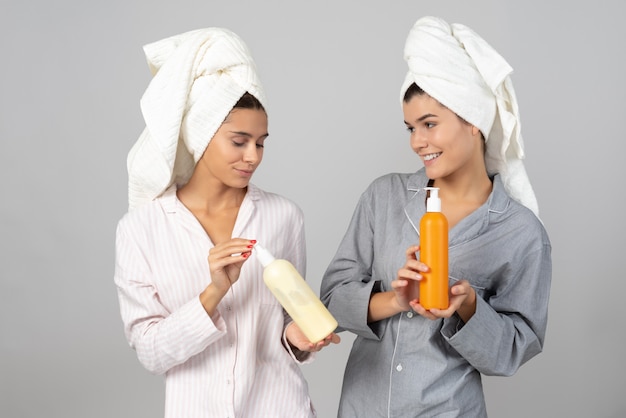 Dos amigas sosteniendo botellas de cosméticos