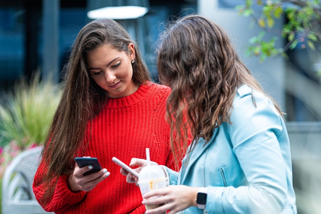 Dos amigas usan un teléfono inteligente para reírse y hablar sobre el concepto de tecnología con los millennials siempre conectados