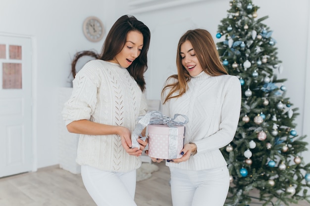 Dos amigos abren regalos de Navidad.