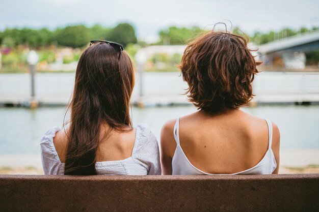 Dos amigos adolescentes sentados en un banco Están mirando el río