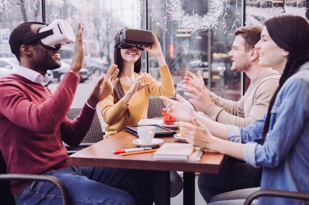 Dos amigos alegres y alegres se divierten sentados y con gafas de realidad virtual