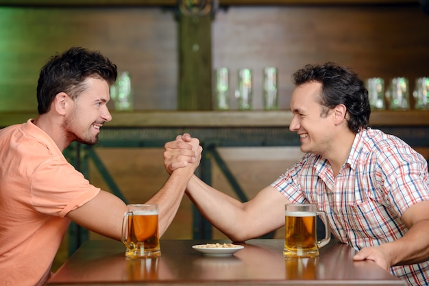 Dos amigos bebiendo cerveza y divirtiéndose en el pub.