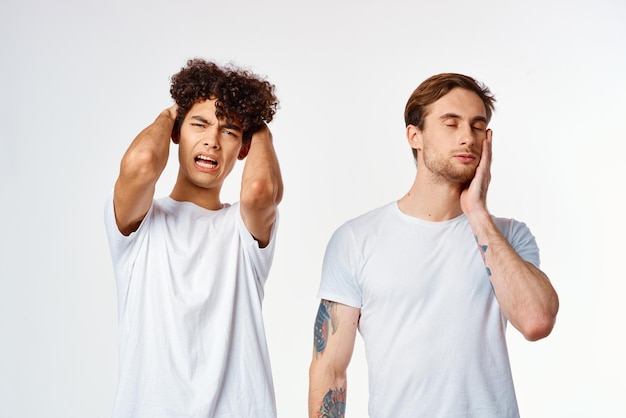 Dos amigos con camisetas blancas sostienen sus emociones en la cabeza.