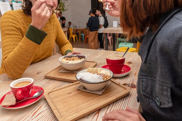 Dos amigos desayunando tazones de batido de acai y café