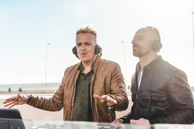 Dos amigos disc jockeys tocando música para turistas en la fiesta del club al aire libre Música en vivo y concepto divertido Concepto de entretenimiento y fiesta