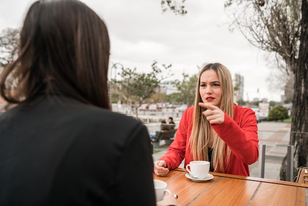 Dos amigos enojados discutiendo mientras está sentado en la cafetería.