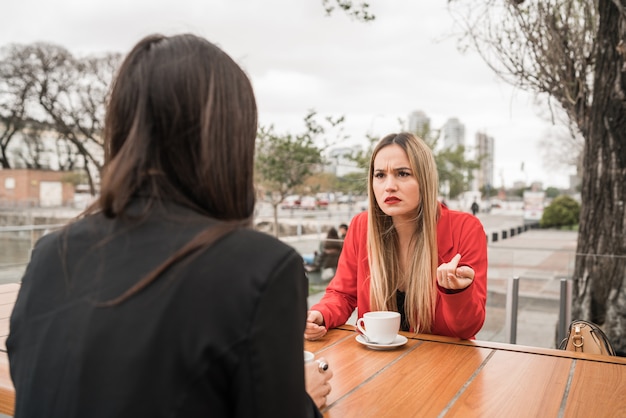 Foto dos amigos enojados discutiendo mientras está sentado en la cafetería.