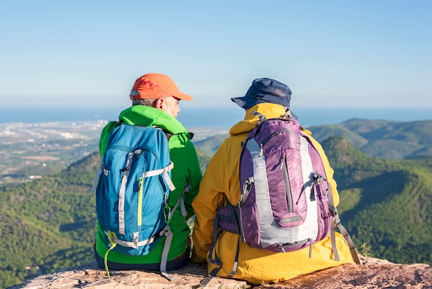 Dos amigos excursionistas sentados en la cima de una montaña con una gran vista