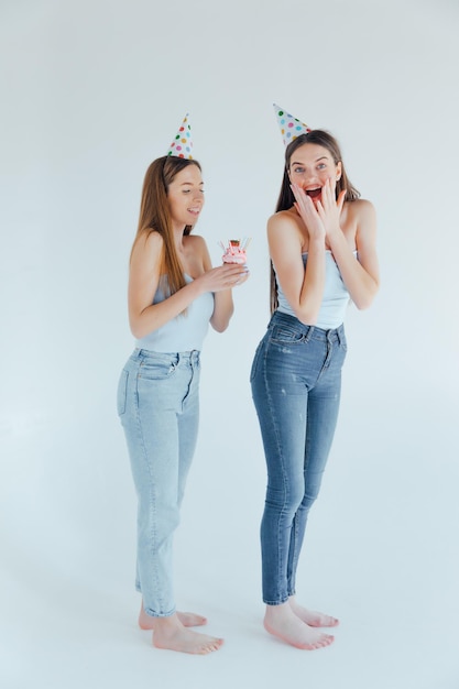 Dos amigos felices celebrando cumpleaños con sombreros de fiesta