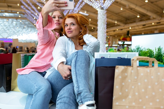 Dos amigos felices se toman selfie mientras compran en el centro comercial