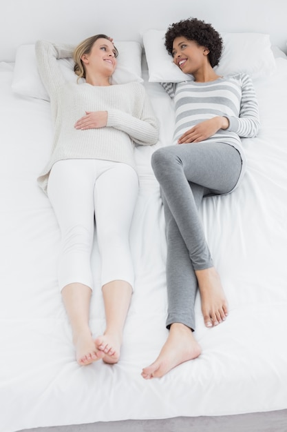 Dos amigos femeninos jovenes casuales que mienten en cama