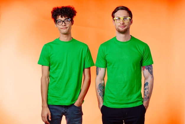 dos amigos con gafas en camisas verdes están de pie junto a la moda foto de alta calidad