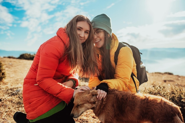 Dos amigos juegan con un perro en la naturaleza.