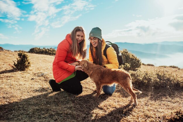 Dos amigos juegan con un perro en la naturaleza.