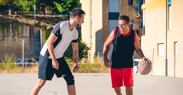 Dos amigos jugando baloncesto en una pista callejera